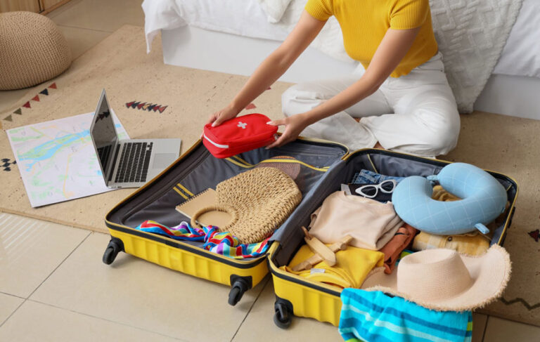 Frau packt ihre Reiseapotheke für den Sommerurlaub in den Koffer