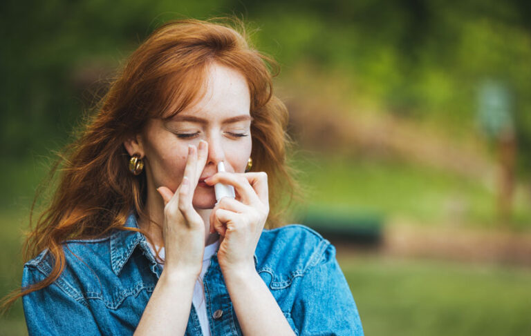 Pollenallergie ganzheitlicher Weg – Frau nutzt Nasenspray in der Natur gegen Heuschnupfen